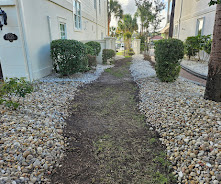Narrow rock-lined path or drainage area between two houses under construction